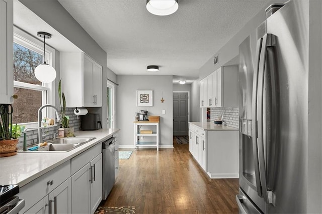 kitchen featuring appliances with stainless steel finishes, sink, white cabinets, and decorative light fixtures