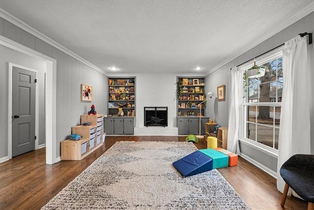 living room with a brick fireplace, crown molding, a textured ceiling, and hardwood / wood-style flooring