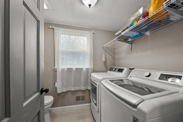 laundry room featuring light tile patterned floors, washer and dryer, and a textured ceiling