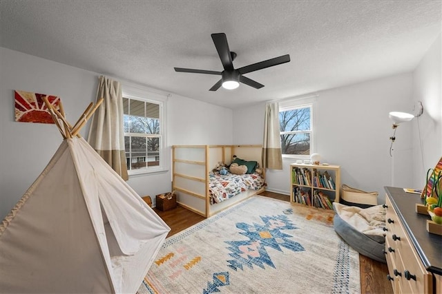 bedroom featuring ceiling fan, dark hardwood / wood-style flooring, and a textured ceiling