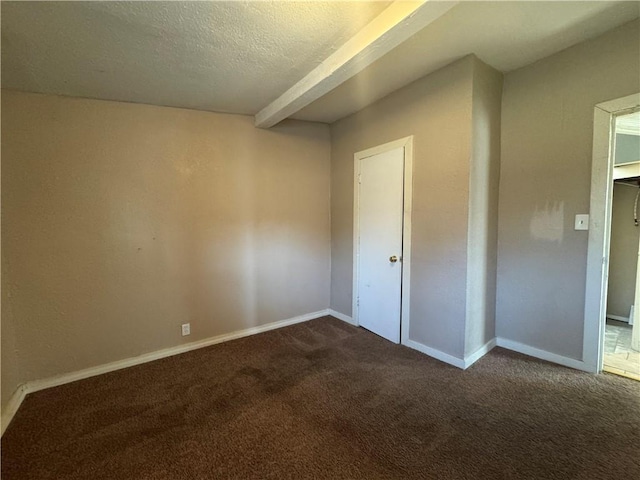 unfurnished bedroom featuring beamed ceiling, dark colored carpet, and a textured ceiling