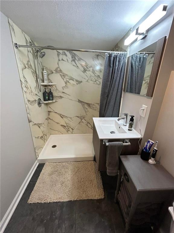 bathroom featuring vanity, curtained shower, and a textured ceiling