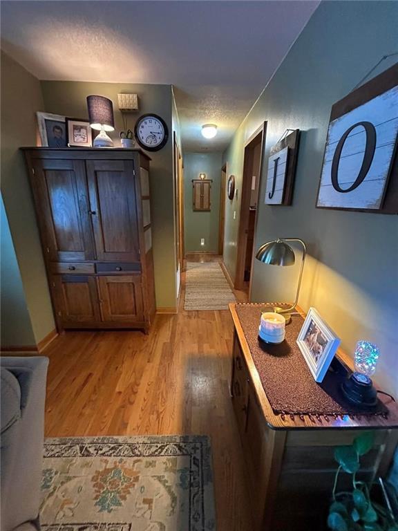 hallway with a textured ceiling and light hardwood / wood-style flooring