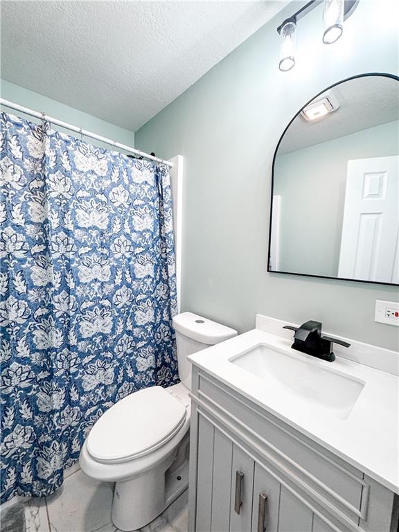 bathroom with vanity, toilet, and a textured ceiling