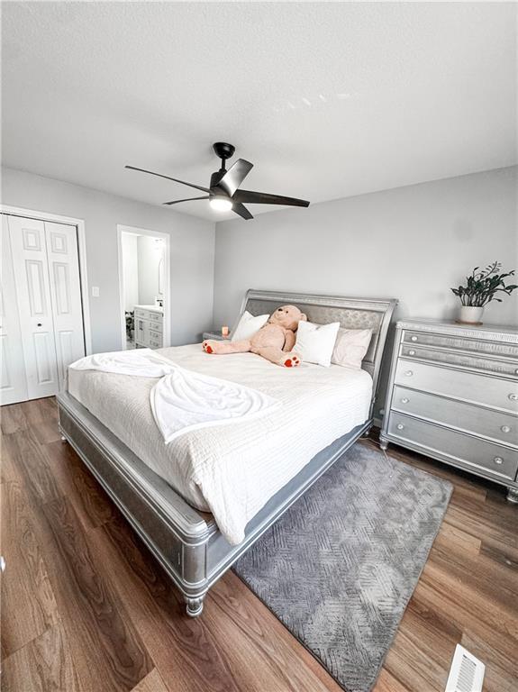 bedroom featuring ensuite bathroom, ceiling fan, dark wood-type flooring, a textured ceiling, and a closet