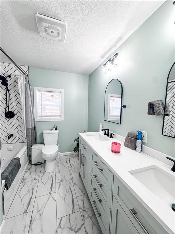 full bathroom featuring vanity, toilet, a textured ceiling, and shower / bath combo with shower curtain