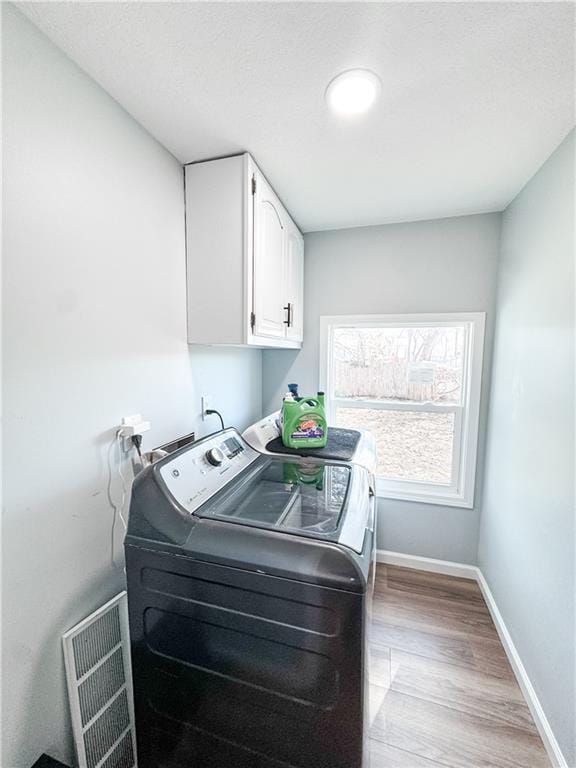 laundry room featuring cabinets, washer and clothes dryer, and light hardwood / wood-style flooring