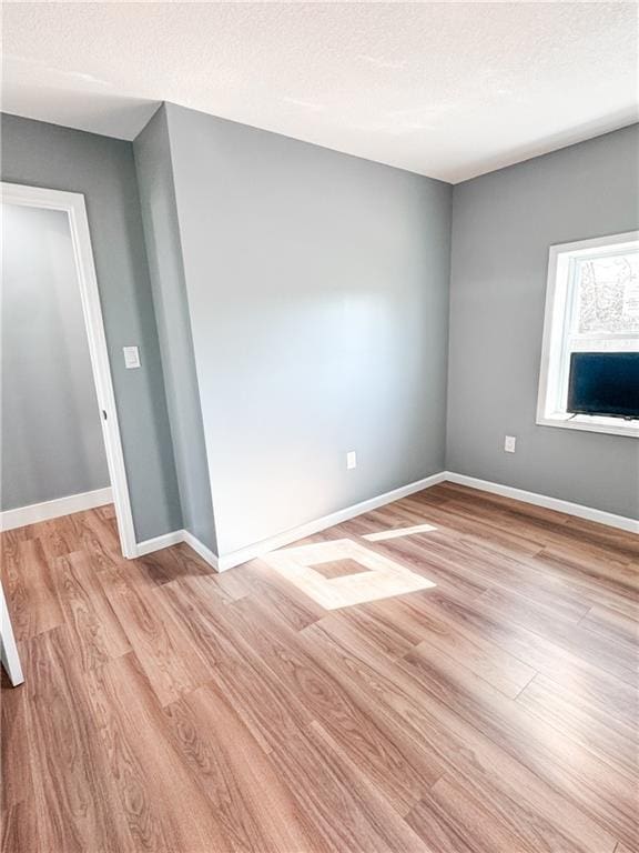 spare room with a textured ceiling and light wood-type flooring