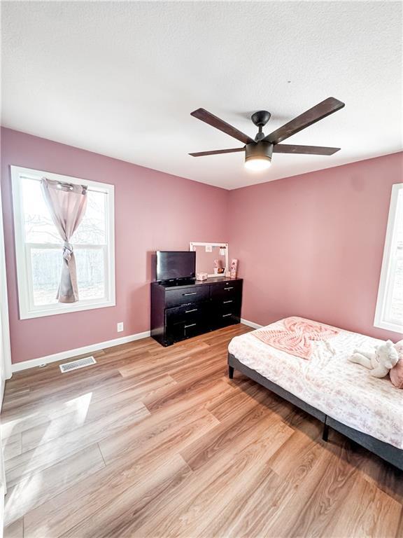 bedroom with ceiling fan, a textured ceiling, and light wood-type flooring