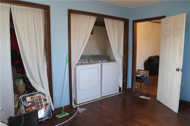 clothes washing area featuring dark hardwood / wood-style floors and washer and clothes dryer