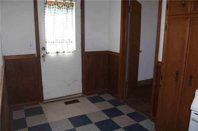 doorway to outside with wood walls