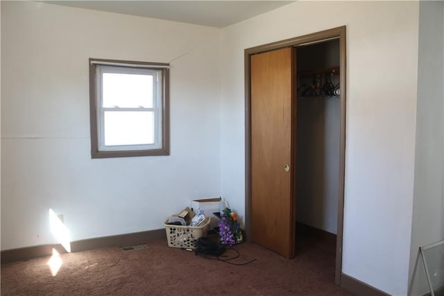 unfurnished bedroom featuring dark carpet and a closet