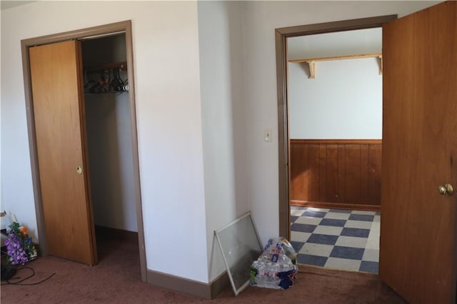 hallway featuring dark carpet and wood walls