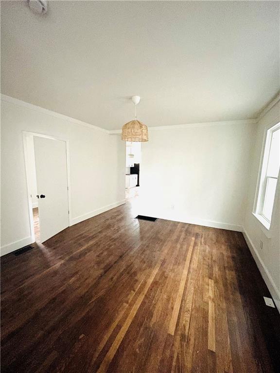 spare room with dark wood-type flooring and crown molding