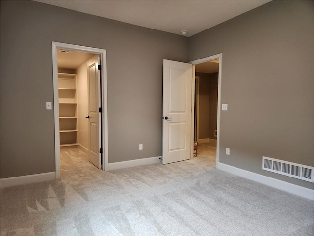 unfurnished bedroom with a walk in closet, light colored carpet, and a closet