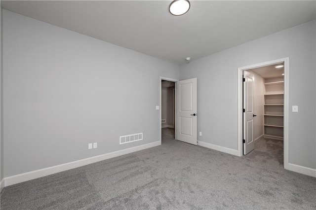 unfurnished bedroom with a walk in closet, light colored carpet, and a closet