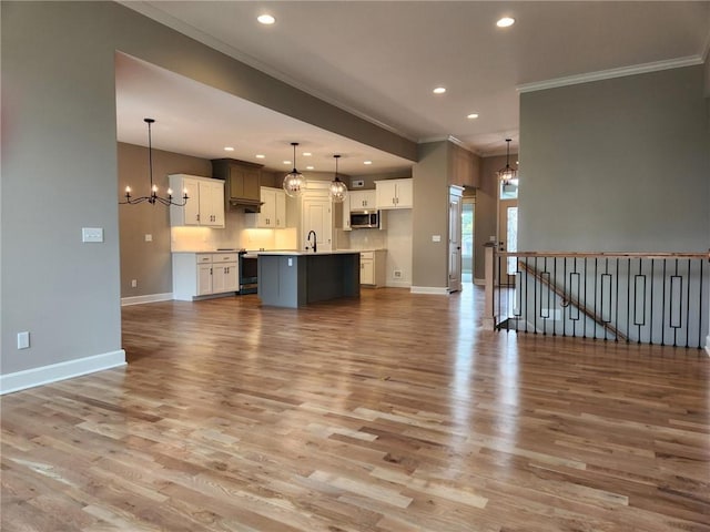 unfurnished living room with an inviting chandelier, sink, crown molding, and light hardwood / wood-style floors