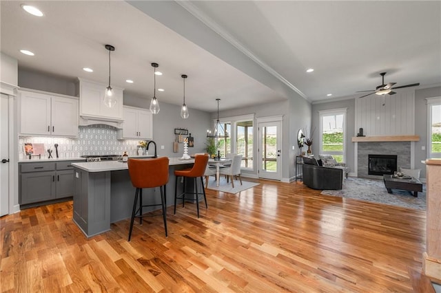 kitchen with a breakfast bar area, white cabinetry, gray cabinetry, an island with sink, and decorative light fixtures