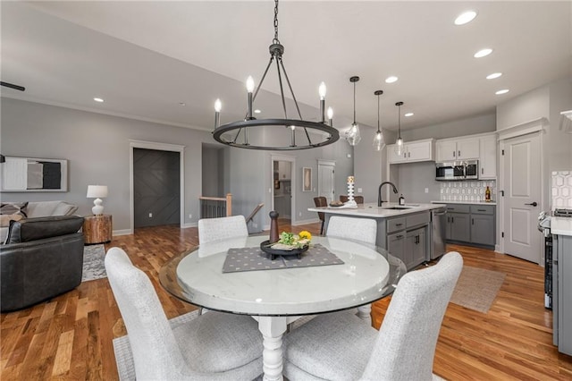 dining area with ornamental molding, light hardwood / wood-style floors, and sink