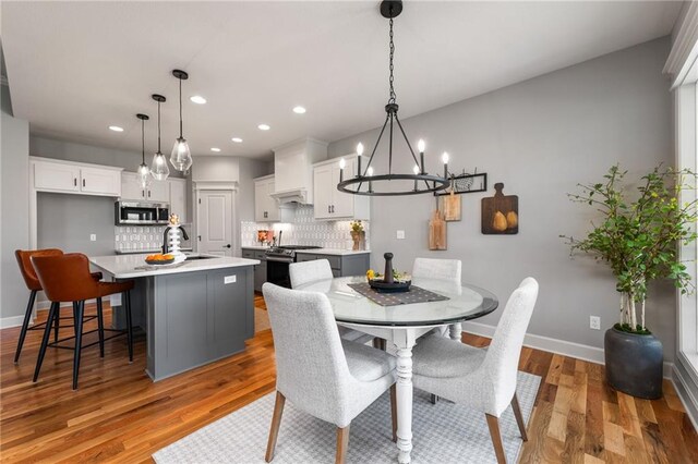 dining area featuring sink, a notable chandelier, and light hardwood / wood-style flooring