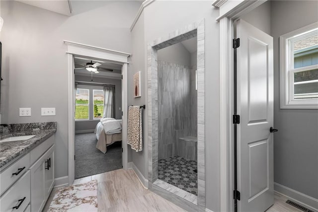 bathroom with vanity, tiled shower, and ceiling fan