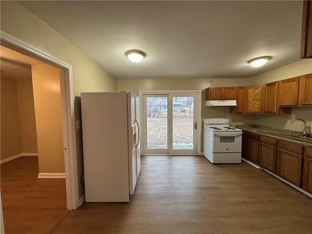 kitchen with brown cabinets, a sink, light wood-type flooring, white appliances, and under cabinet range hood