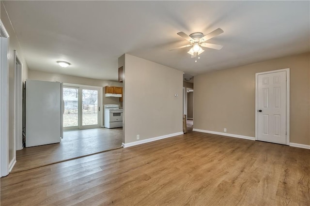 empty room with ceiling fan, light wood finished floors, and baseboards