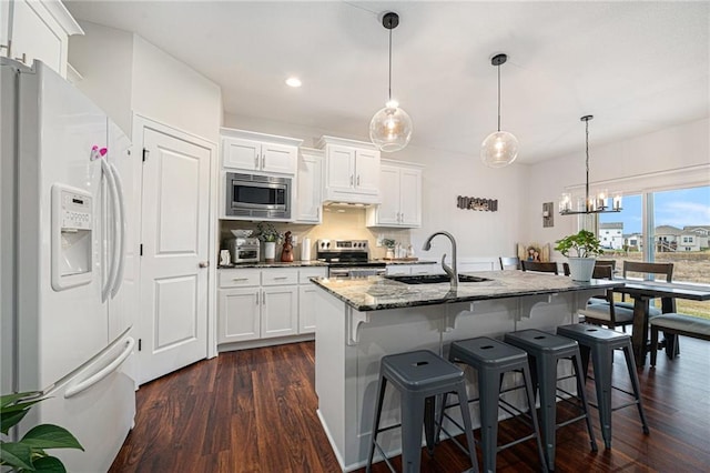 kitchen featuring stainless steel appliances, hanging light fixtures, sink, and white cabinets