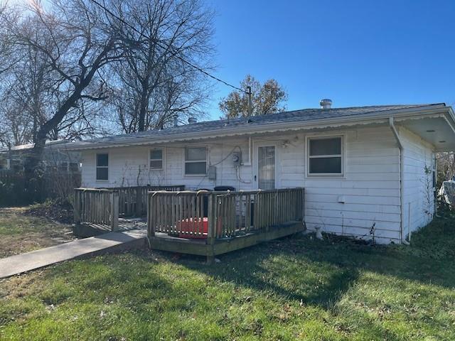 back of property featuring a lawn and a deck