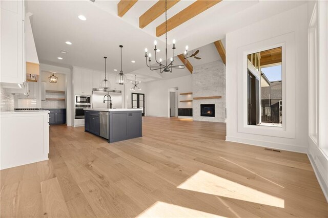 17021 Parkhill St, Overland Park, KS 66221 - kitchen featuring stainless steel appliances, white cabinetry, a chandelier, open floor plan, and light countertops