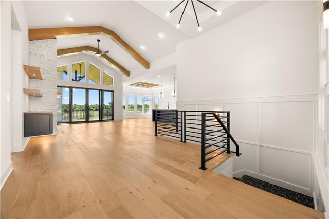 17021 Parkhill St, Overland Park, KS 66221 - staircase featuring beam ceiling, high vaulted ceiling, wood finished floors, a chandelier, and wainscoting