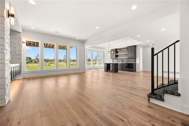 17021 Parkhill St, Overland Park, KS 66221 - unfurnished living room with stairs, light wood finished floors, recessed lighting, and a chandelier