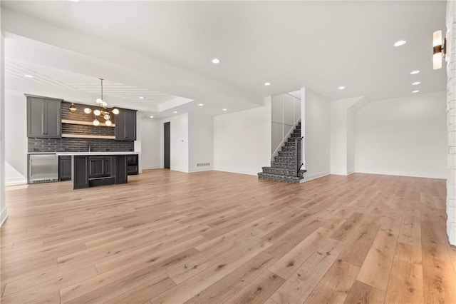 17021 Parkhill St, Overland Park, KS 66221 - unfurnished living room with light wood-style floors, a chandelier, stairway, and recessed lighting