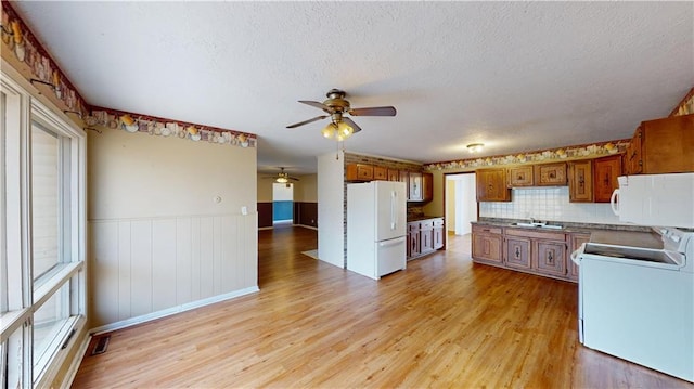 kitchen with sink, tasteful backsplash, a textured ceiling, white appliances, and light hardwood / wood-style floors