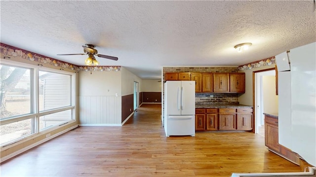 kitchen with white fridge, a textured ceiling, ceiling fan, and light hardwood / wood-style flooring