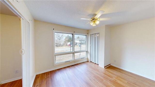 empty room featuring ceiling fan, light hardwood / wood-style flooring, and a textured ceiling