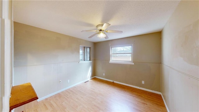 empty room featuring ceiling fan, a textured ceiling, and light wood-type flooring