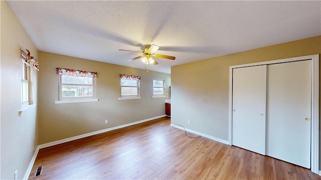 unfurnished bedroom featuring ceiling fan, light hardwood / wood-style floors, a closet, and a textured ceiling