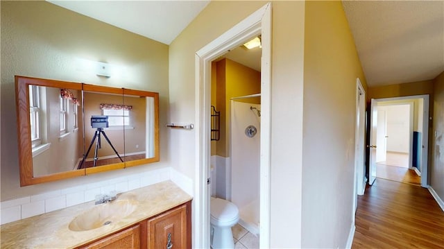 bathroom with a shower, wood-type flooring, vanity, and toilet