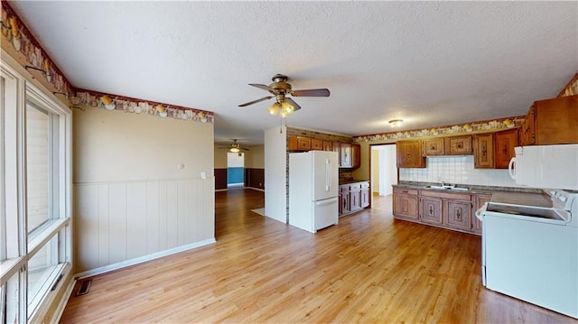 1120 N Oak St, Nevada, MO 64772 - kitchen featuring a ceiling fan, brown cabinets, light wood-type flooring, a sink, and white appliances