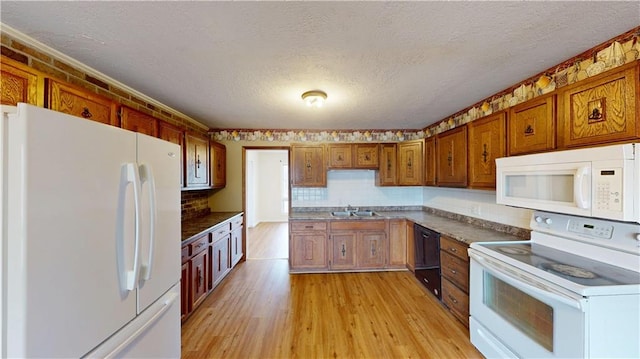 1120 N Oak St, Nevada, MO 64772 - kitchen with white appliances, light wood-style floors, a textured ceiling, brown cabinets, and a sink