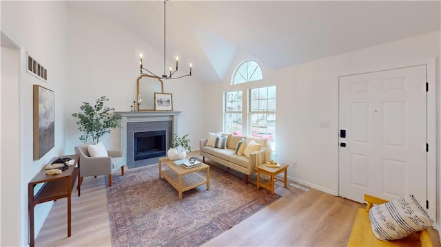 living room featuring wood-type flooring, high vaulted ceiling, and a chandelier