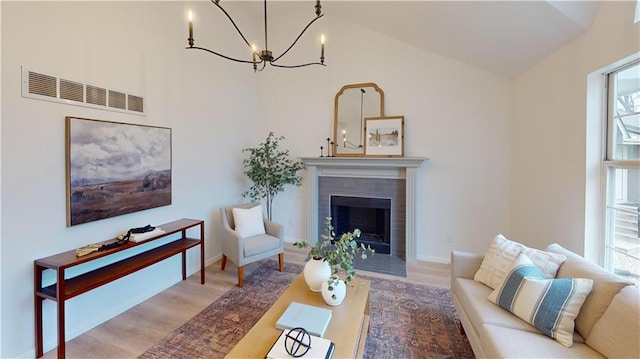 living room with hardwood / wood-style floors, a tile fireplace, and a notable chandelier