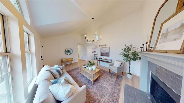 living room with a tile fireplace, high vaulted ceiling, hardwood / wood-style floors, and an inviting chandelier