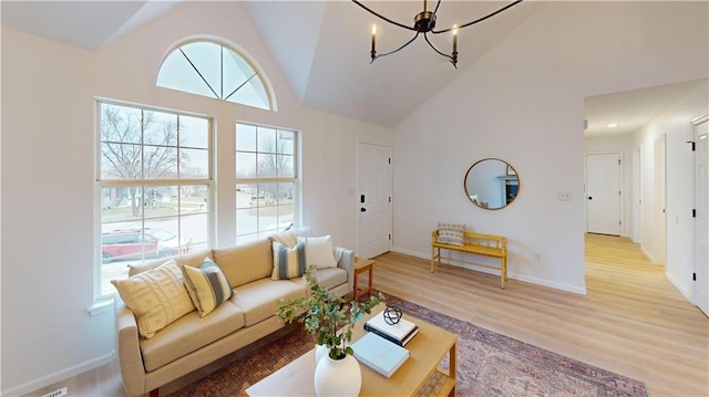 living room featuring high vaulted ceiling, an inviting chandelier, and light hardwood / wood-style floors