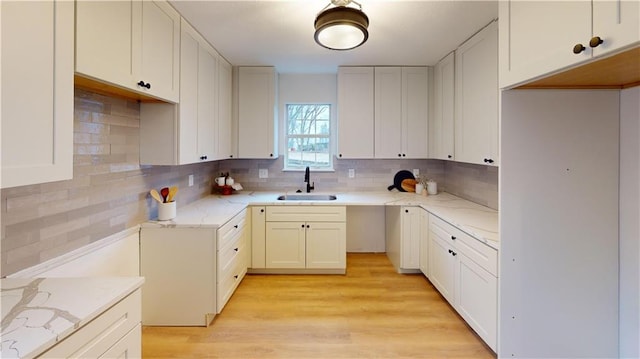 kitchen featuring white cabinetry, light hardwood / wood-style floors, sink, and backsplash