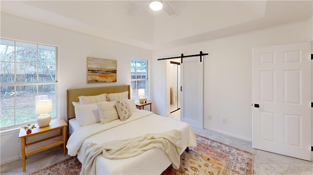 bedroom featuring multiple windows, a barn door, light colored carpet, and ceiling fan