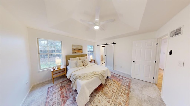 bedroom featuring a raised ceiling, a barn door, light carpet, and ceiling fan