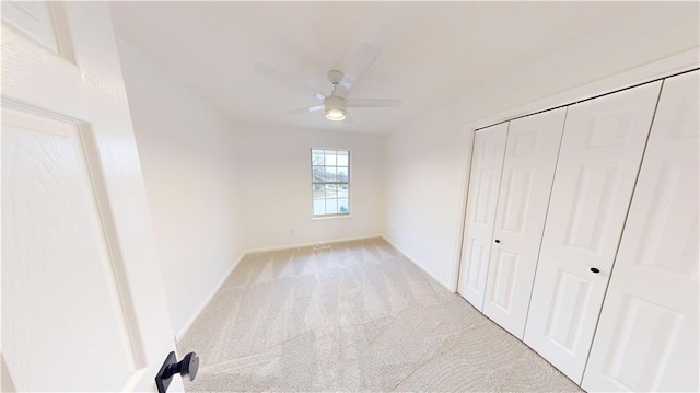 unfurnished bedroom featuring ceiling fan, a closet, and light carpet