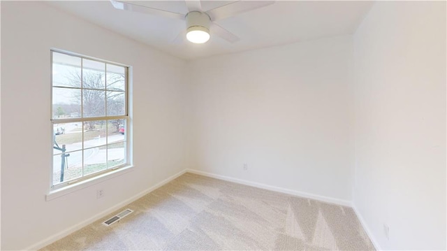 carpeted spare room with ceiling fan and plenty of natural light